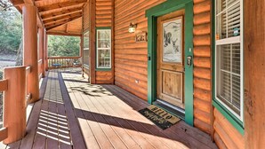 A wooden cabin with a porch, a green door, and a welcome mat. - Family-friendly Cabin By Golf Course & Marina (Eureka Springs)