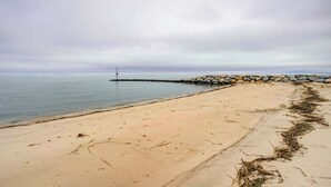 A beach with a stone wall and a lighthouse in the distance. - Bowers Beach Vacation Rental: 2 Blocks Away! (Frederica)