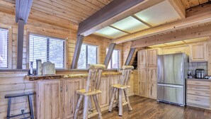 Une cuisine rustique avec des meubles en bois, un réfrigérateur en acier inoxydable et un coin bar avec des tabourets.