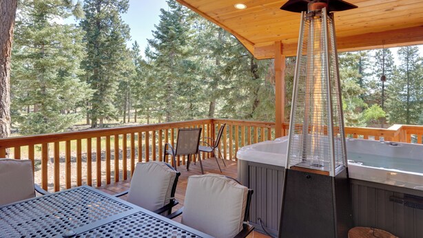 Une terrasse en bois avec un jacuzzi, des sièges d’extérieur et une vue sur une forêt.