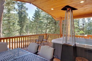 A wooden deck with a hot tub, outdoor seating, and a view of a forest. - Spacious Duck Creek Village Cabin w/ Hot Tub! (Duck Creek Village)