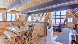 Une vaste cabane en bois comprenant un coin repas, un piano et un espace salon confortable.