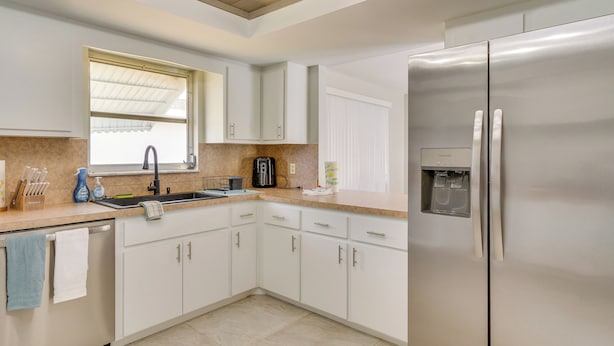 Una cocina moderna con gabinetes blancos, electrodomésticos de acero inoxidable y un dispensador de agua empotrado.