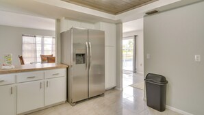 Una cocina moderna con armarios blancos, un refrigerador de acero inoxidable y un cubo de basura.