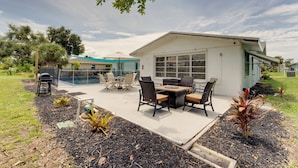 Una casa moderna con un patio, mobiliario exterior y piscina.