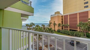 A balcony with a view of the ocean, a parking lot, and buildings with a modern design. - Balcony & Resort Amenities at Myrtle Beach Condo! (Myrtle Beach)