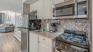 A modern kitchen with white cabinets, a stainless steel refrigerator, a microwave, and a stove. - Balcony & Resort Amenities at Myrtle Beach Condo! (Myrtle Beach)