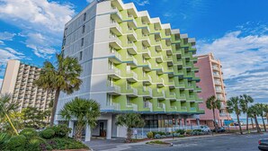 A multi-story hotel with a distinctive green and white facade, multiple balconies, and a view of the ocean. - Balcony & Resort Amenities at Myrtle Beach Condo! (Myrtle Beach)