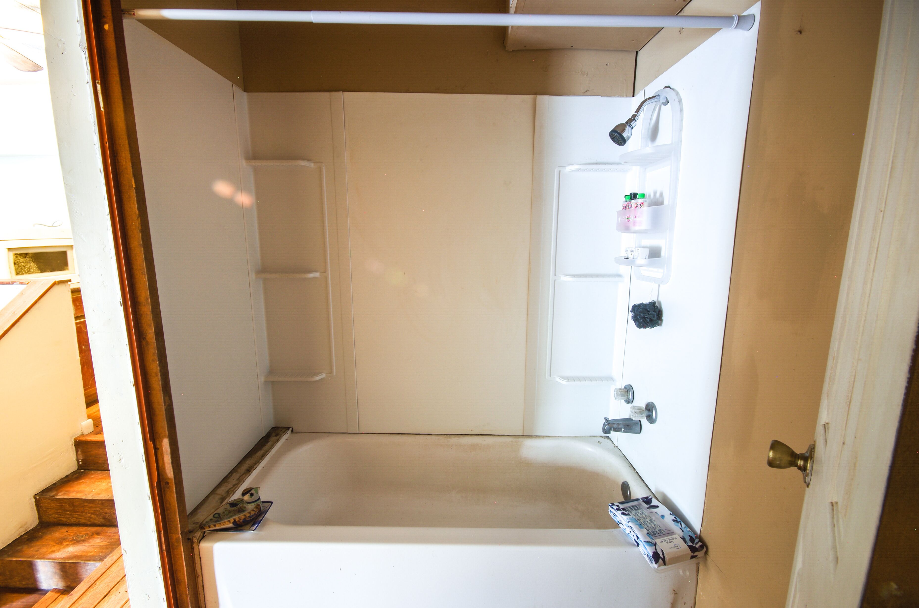 A small, narrow bathroom with a bathtub, a shower, and a toilet.
