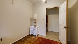 A room with a ceiling fan, a white nightstand with drawers, a lamp, and a red rug. - Hazlehurst Vacation Rental w/ Shared Yard! (Hazlehurst)