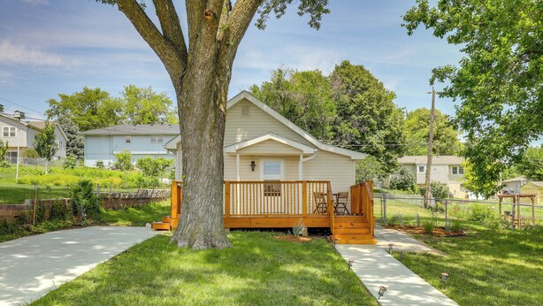 A single-story house with a front porch, a large tree in front, and a paved driveway. - Cozy Omaha Vacation Rental: 6 Miles to Downtown! (Omaha)