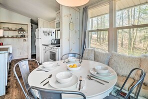 Enjoy meals in this inviting dining area with a round table for four, comfortable sofa, and a view of the surrounding woods.