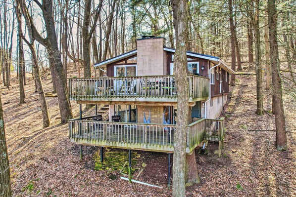 Perched above the forest, this cabin offers a view of the surrounding trees from its elevated balcony.
