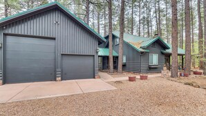 A two-story cabin with a large garage door and a covered porch. - Furnished Patio & Fire Pit: Pinetop Cabin! (Pinetop)