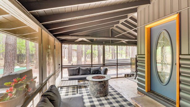 A covered outdoor seating area with a stone fire table, a checkered rug, and a sofa. - Furnished Patio & Fire Pit: Pinetop Cabin! (Pinetop)