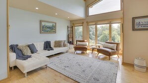 A spacious living room with a white sofa, a brown leather chair, and a patterned rug. - Stunning Sheridan Ranch Villa: Mountain View! (Sheridan)