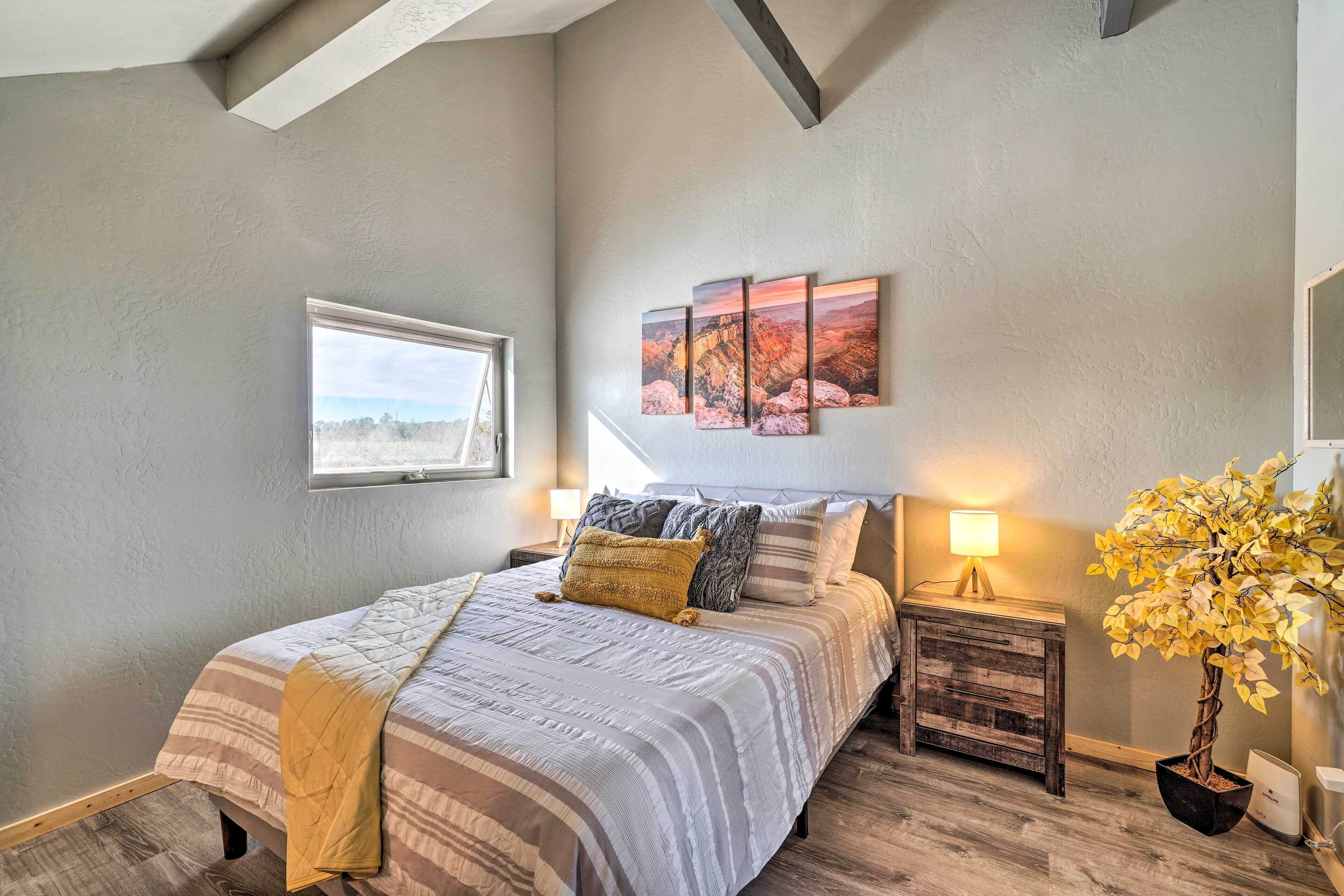 A bedroom with a bed, a nightstand, a lamp, a window, and a painting on the wall.