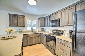 A modern kitchen with dark wooden cabinets, stainless steel appliances, and a light-colored countertop. - Cozy Blackfoot Apartment: Pets Welcome! (Blackfoot)