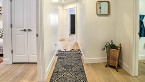 A hallway with a patterned rug, a wicker basket with plants, and a mirror on the wall. - Cozy Blackfoot Apartment: Pets Welcome! (Blackfoot)
