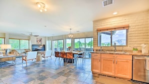 A spacious kitchen with a large island, a dining area with a table and chairs, and a view of the mountains through large windows. - Patio & Panoramic Desert Views: Sedona Getaway! (Sedona)
