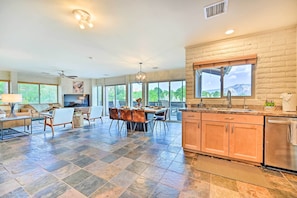 A spacious kitchen with a large island, a dining area with a table and chairs, and a view of the mountains through large windows. - Patio & Panoramic Desert Views: Sedona Getaway! (Sedona)