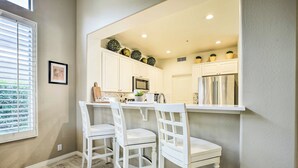 A kitchen with white cabinets, a stainless steel refrigerator, and two white chairs. - Pool & Pickleball Access: Quiet Scottsdale Home! (Scottsdale)