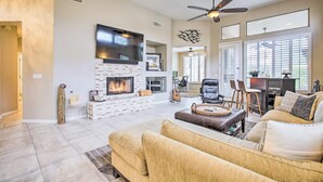 A spacious living room with a fireplace, comfortable seating, and a large TV mounted on the wall. - Pool & Pickleball Access: Quiet Scottsdale Home! (Scottsdale)