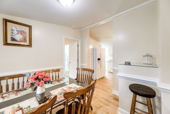 A dining area with a wooden table, chairs, and a vase of flowers. - Cozy New Bern Getaway < 2 Mi to Trent River! (New Bern)