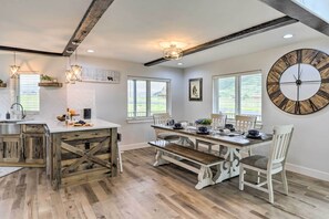 Uma cozinha espaçosa com piso de madeira, uma grande mesa de jantar e um relógio rústico na parede.