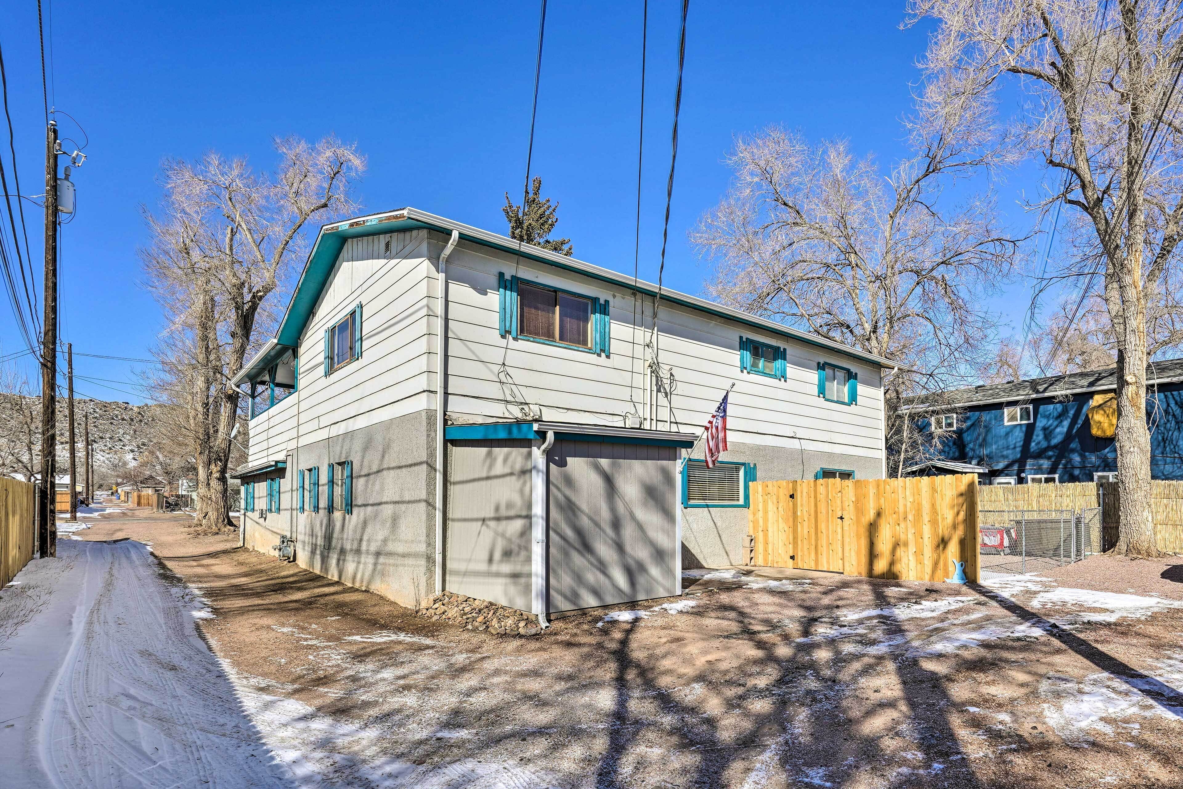 A two-story house with a garage, a wooden fence, and a clear sky.