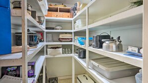 Une cuisine bien aménagée, dotée de nombreuses étagères, de divers appareils de cuisine et de boîtes de rangement.