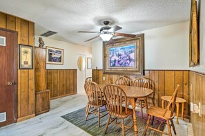A dining area with wooden paneling, a ceiling fan, and framed artwork on the walls. - Pet-friendly Duplex - Near Skyline Drive! (Canon City)
