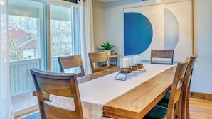 Un coin repas avec une table en bois, six chaises et un grand tableau abstrait accroché au mur.