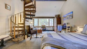 A bedroom with a large bed, a wooden spiral staircase, a desk, and a chair. - Durango Lofted Studio ~ 9 Mi to Purgatory Resort! (Durango)