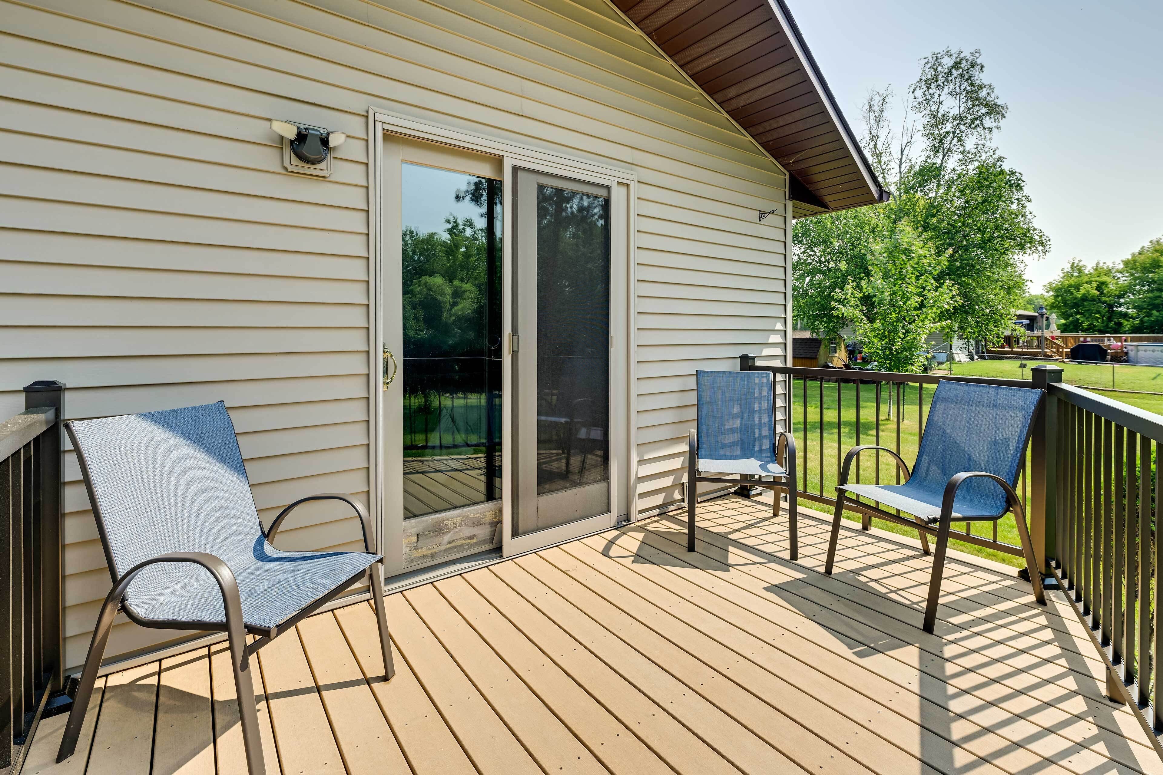 A wooden deck with two chairs and a sliding glass door leading to a covered area.