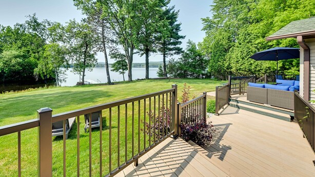 A deck with a view of a lake, surrounded by trees and a grassy lawn. - Charming Wausau Cottage: On-site Lake Access! (Wausau)