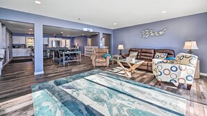 A spacious living area with a kitchen in the background, a patterned rug, and two armchairs with a side table. - Charming Wausau Cottage: On-site Lake Access! (Wausau)