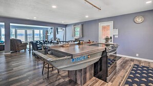 A modern kitchen with a central island, a dining area with chairs, and a large window providing a view. - Charming Wausau Cottage: On-site Lake Access! (Wausau)