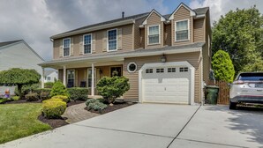 Une maison à deux étages avec un porche à l’avant, un garage et une allée.