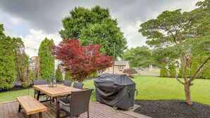 Une terrasse extérieure avec une table et des chaises en bois, un barbecue et un banc abrité.