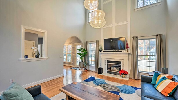 A spacious living room with a fireplace, a large TV, and a comfortable seating area. - Tranquil Greensboro Home w/ Fire Pit! (Greensboro)
