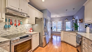 A modern kitchen with white cabinets, stainless steel appliances, and a wooden floor. - Tranquil Greensboro Home w/ Fire Pit! (Greensboro)