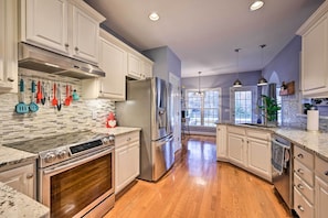 A modern kitchen with white cabinets, stainless steel appliances, and a wooden floor. - Tranquil Greensboro Home w/ Fire Pit! (Greensboro)