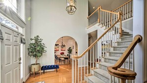 A spacious hallway with a staircase, a dining area, and a large potted plant. - Tranquil Greensboro Home w/ Fire Pit! (Greensboro)