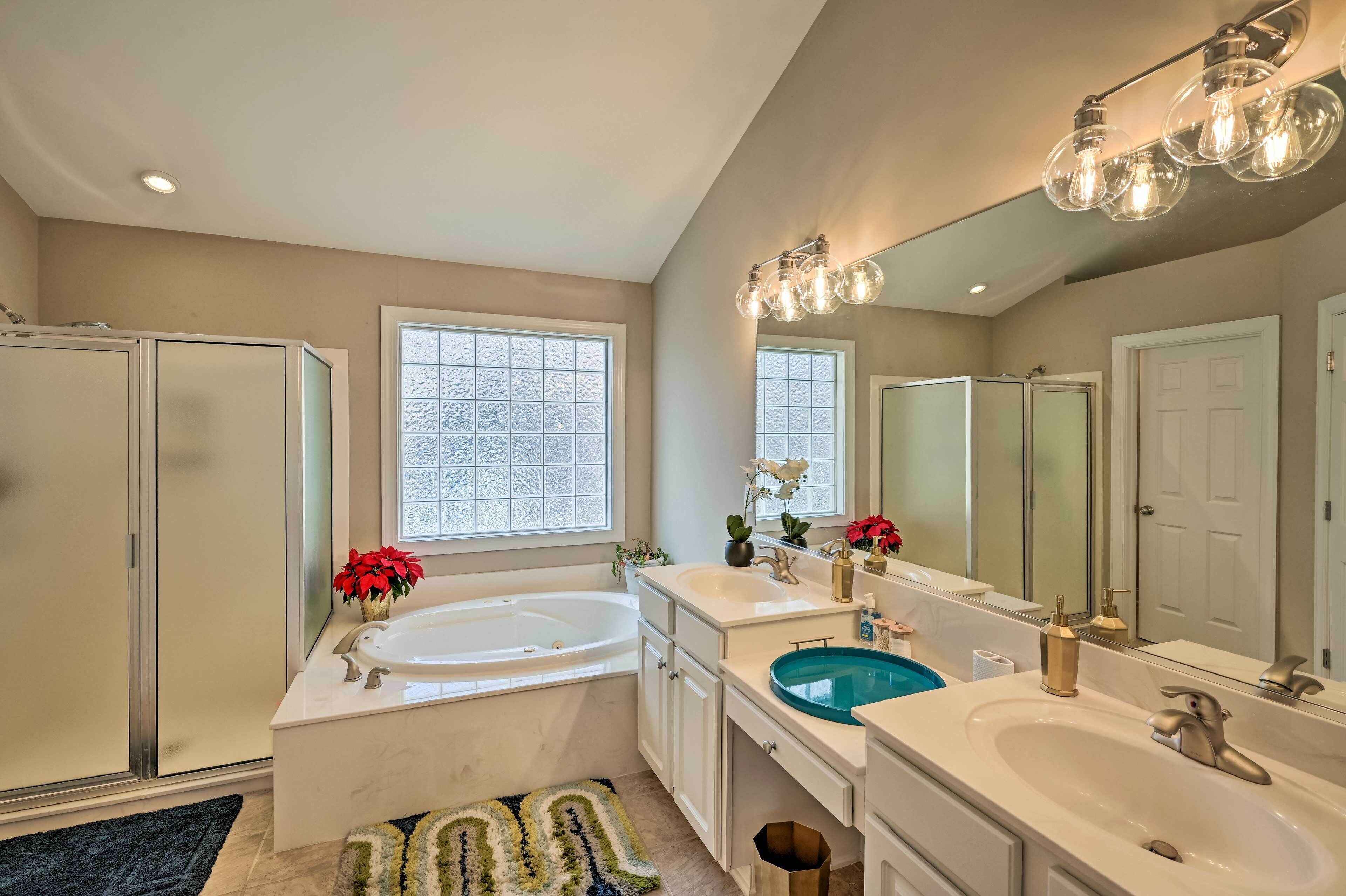 A modern bathroom with two sinks, a bathtub, and a large mirror.