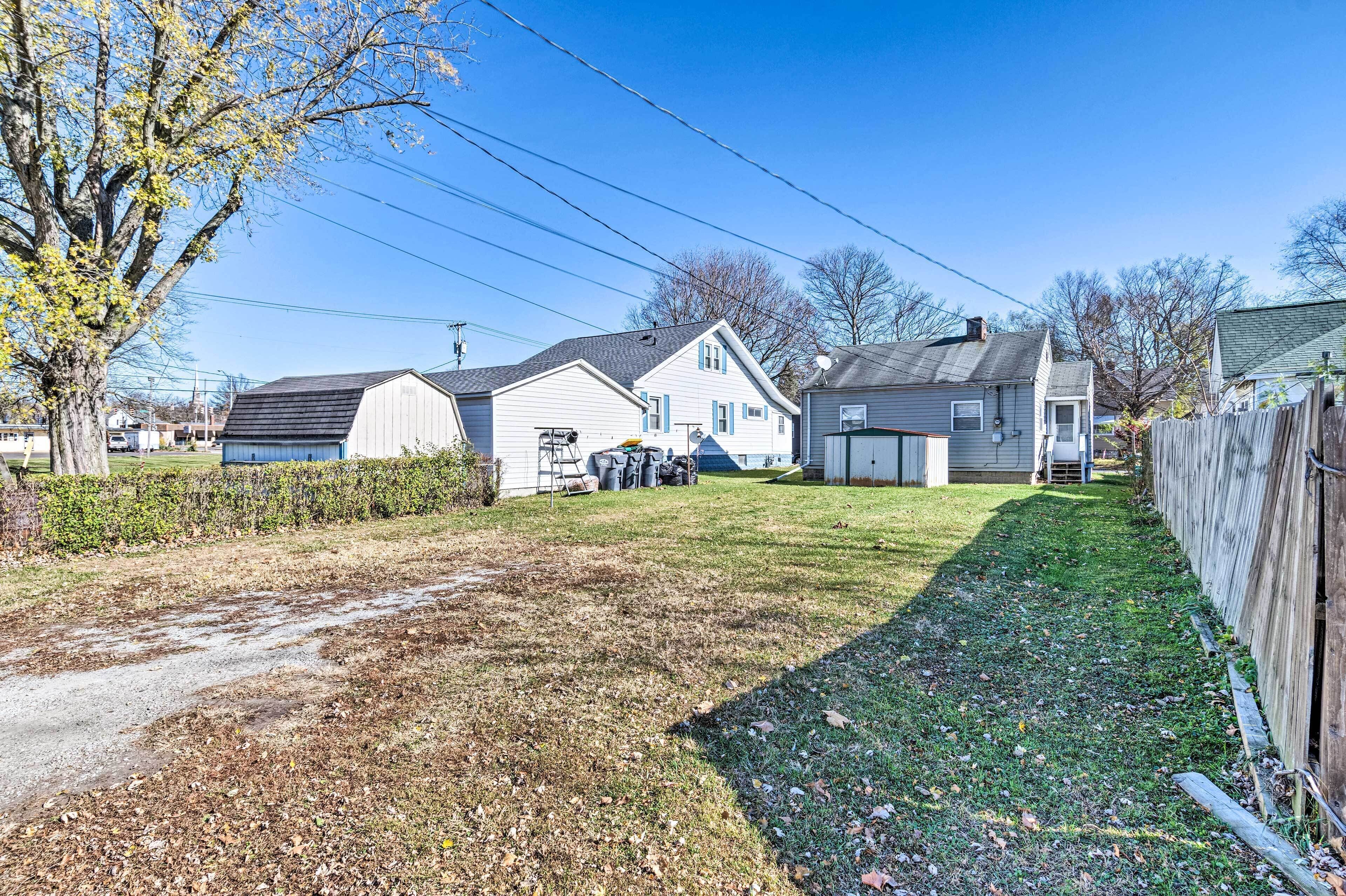 A residential area with a grassy yard, a wooden fence, and two houses with attached garages.