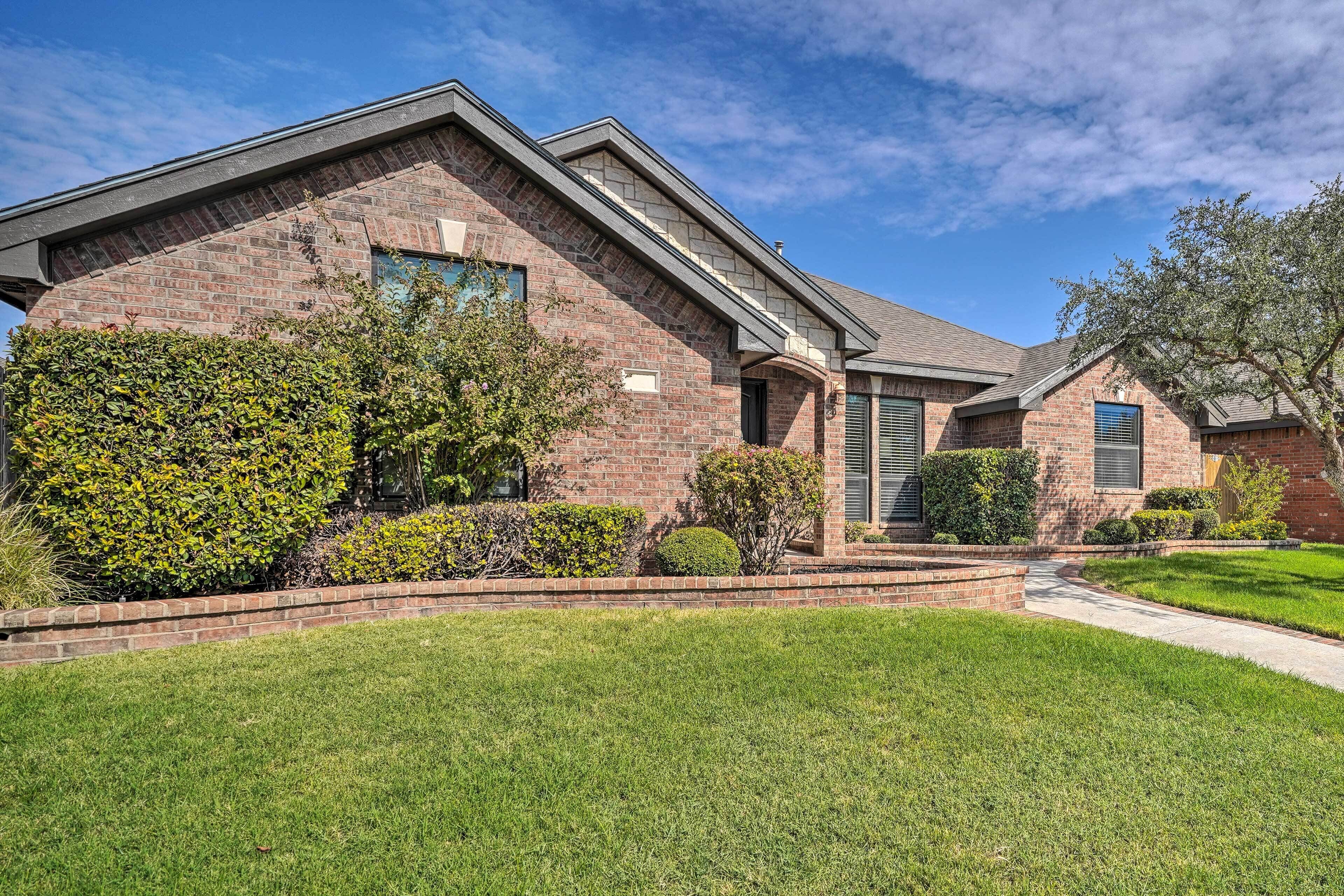 A two-story brick house with a well-maintained lawn and a small garden area.