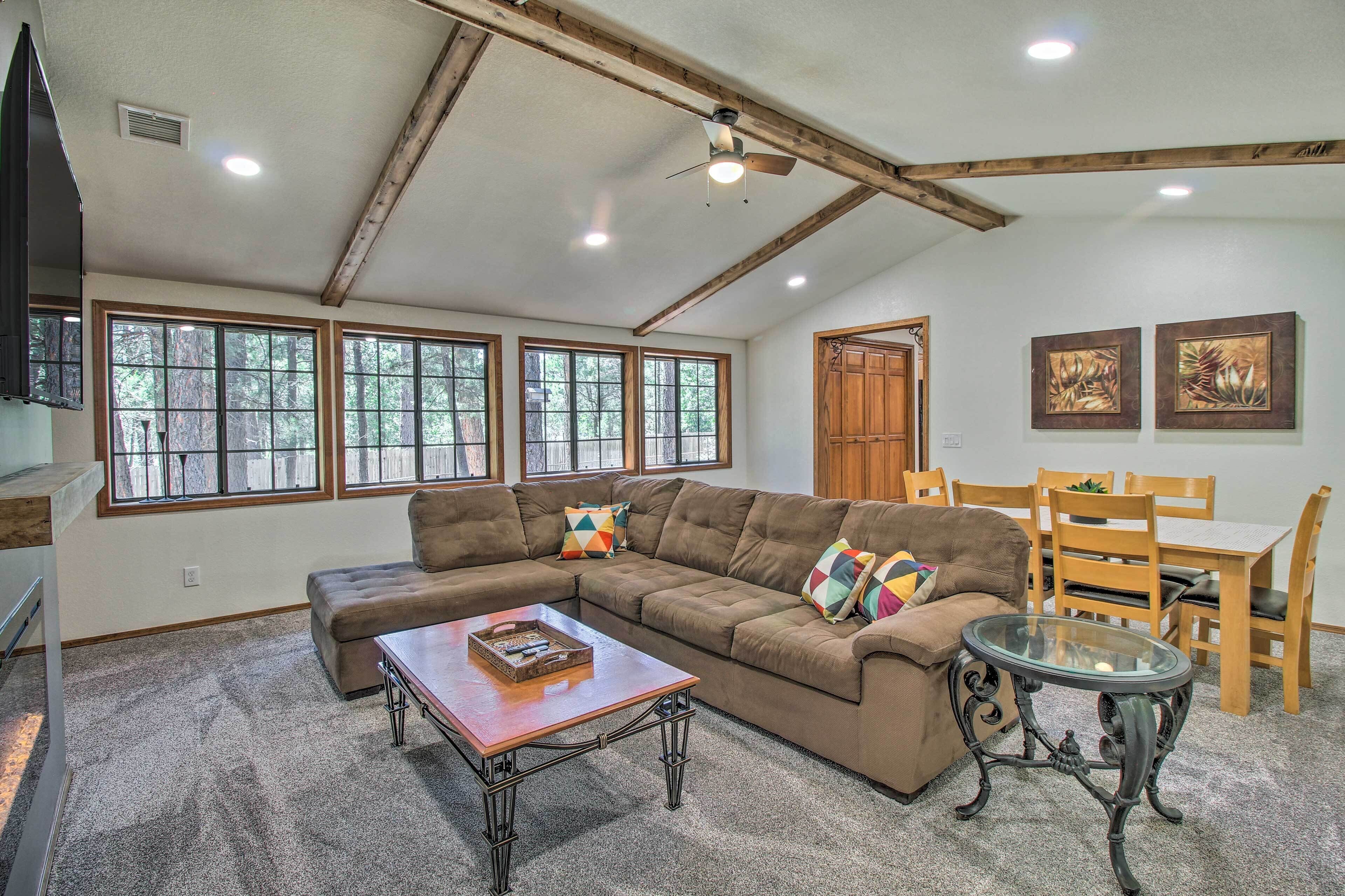 A spacious living room with a sectional sofa, a glass coffee table, and a dining area with wooden chairs and a table.