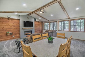 A dining area with a table, chairs, and a fireplace. - Screened Porch, Fenced Yard: Lakeside Retreat! (Lakeside)