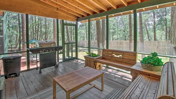 A covered outdoor area with a wooden bench, a grill, and a table. - Screened Porch, Fenced Yard: Lakeside Retreat! (Lakeside)